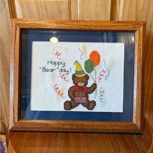 Framed handmade cross-stitch featuring a teddy bear celebrating a birthday